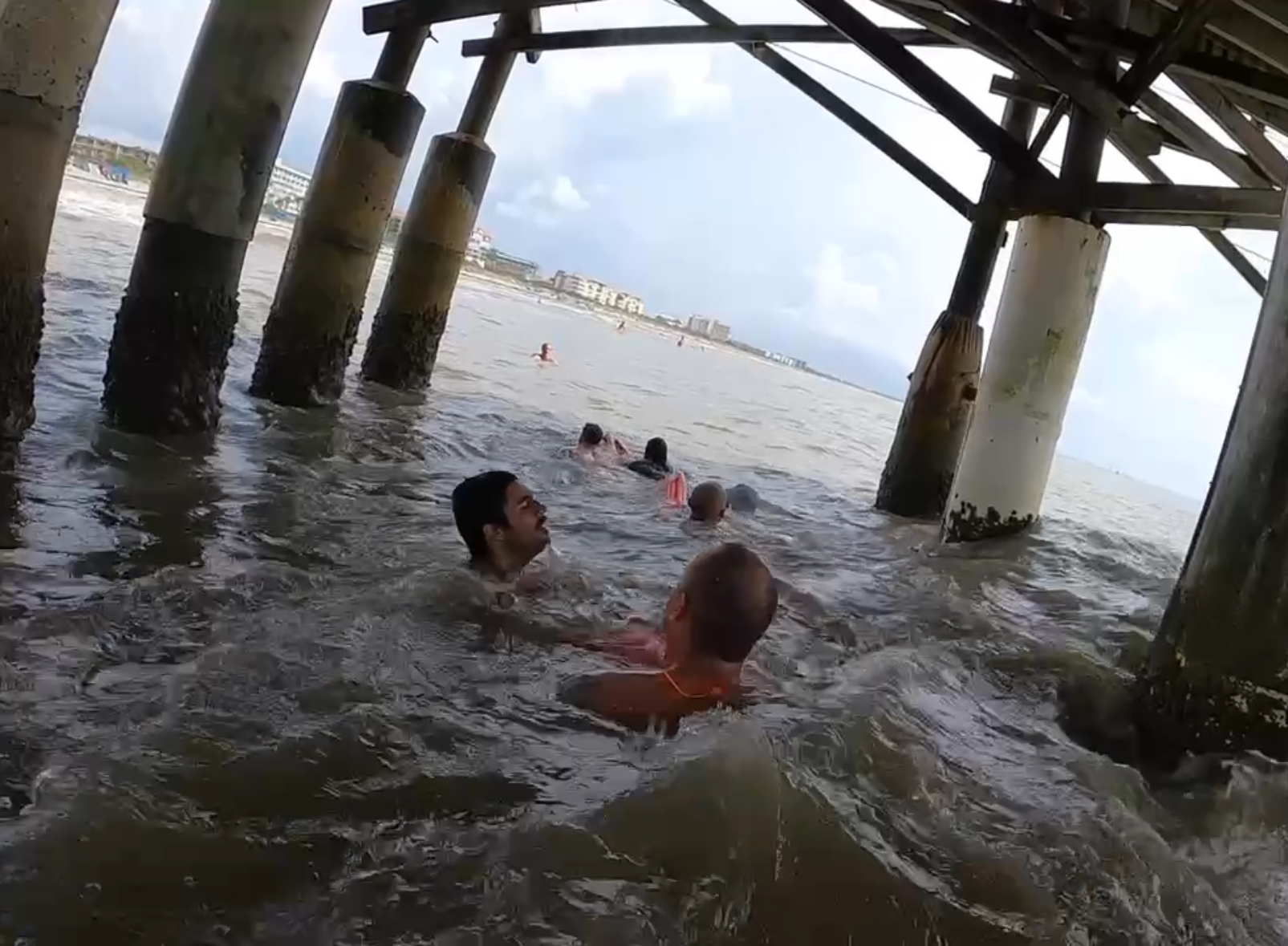 Students applying technical swimming tactics underneath an elevated structure over the water.